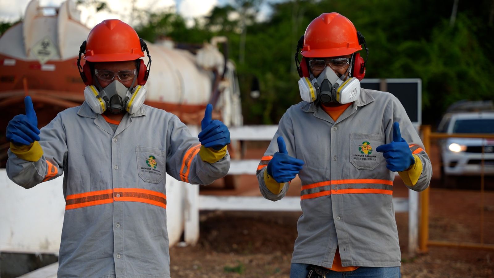 Dois colaboradores da LR Service com capacete, máscara e luvas fazendo sinal de positivo