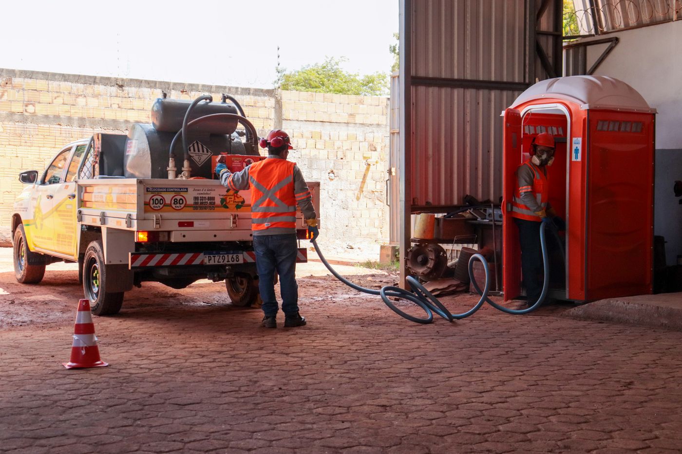 Equipe fazendo a sucção e higienização de uma cabine sanitária
