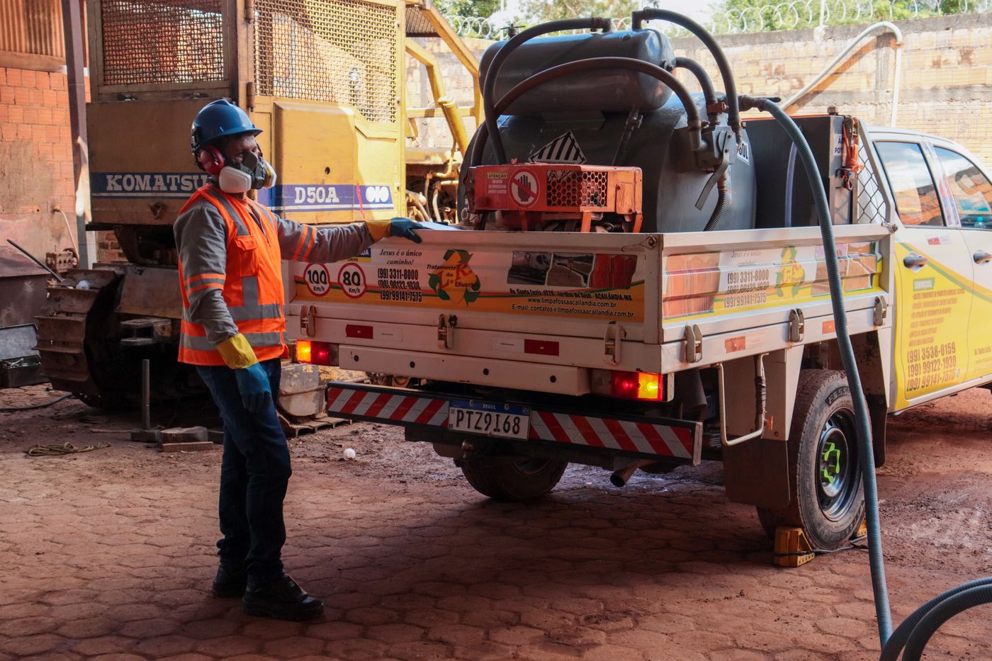 Colaborador com EPI completo operando caminhonete de sucção